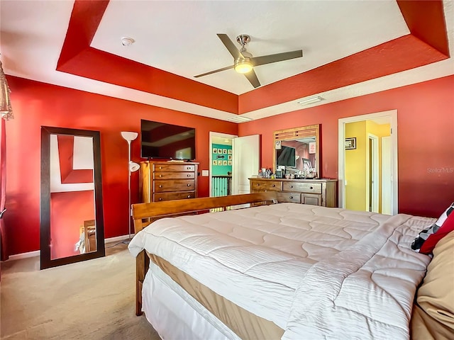 carpeted bedroom with ceiling fan and a raised ceiling