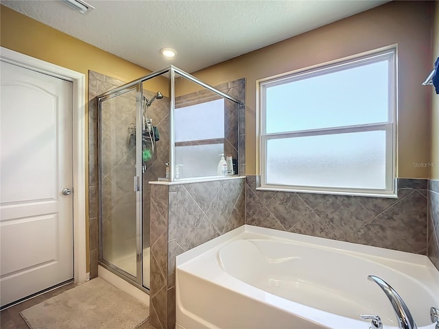 bathroom featuring separate shower and tub and a textured ceiling