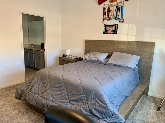 carpeted bedroom featuring sink and ensuite bath