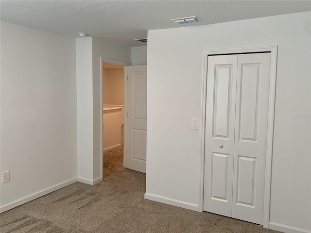 unfurnished bedroom featuring carpet flooring, a closet, and a textured ceiling