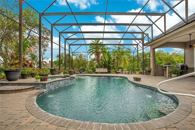 view of pool with ceiling fan, glass enclosure, a patio area, grilling area, and pool water feature