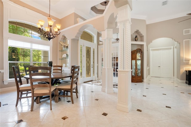 tiled dining room featuring an inviting chandelier, crown molding, a towering ceiling, and ornate columns