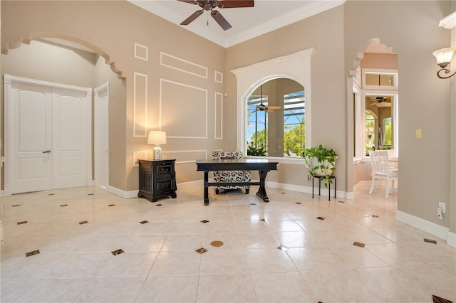 tiled entrance foyer featuring ceiling fan, ornamental molding, and a high ceiling