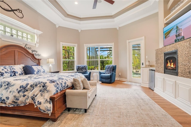 bedroom with light hardwood / wood-style flooring, access to outside, ornamental molding, a raised ceiling, and a high ceiling