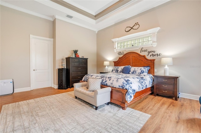 bedroom featuring a raised ceiling, ornamental molding, and light hardwood / wood-style floors