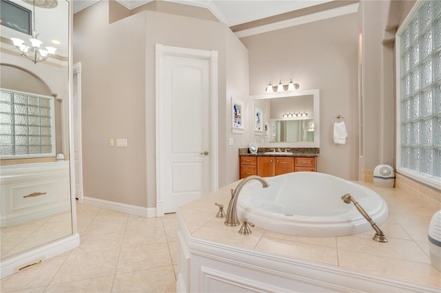 bathroom featuring tiled tub, tile patterned flooring, vanity, ornamental molding, and a chandelier