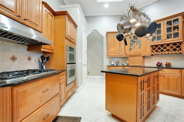 kitchen featuring a center island, dark stone countertops, ornamental molding, appliances with stainless steel finishes, and pendant lighting