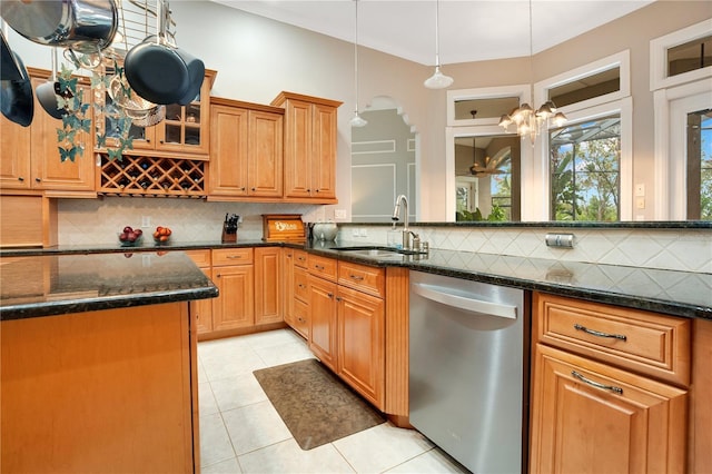 kitchen with dishwasher, sink, dark stone counters, and decorative light fixtures