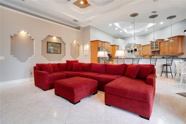 tiled living room with crown molding, a raised ceiling, an inviting chandelier, and a high ceiling