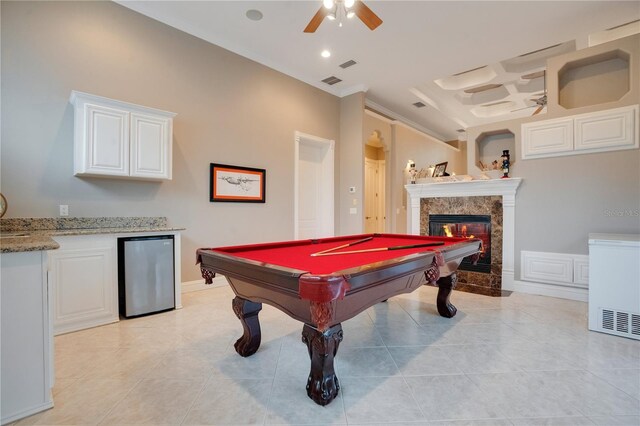 game room with light tile patterned flooring, coffered ceiling, ceiling fan, and a fireplace