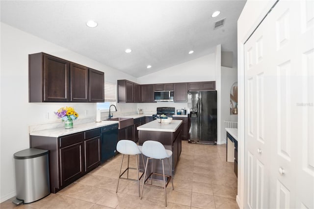 kitchen with lofted ceiling, sink, a breakfast bar area, a center island, and black appliances