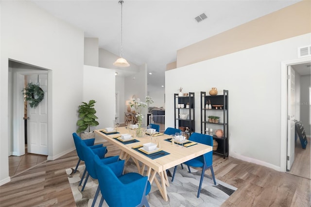 dining room featuring high vaulted ceiling and light wood-type flooring