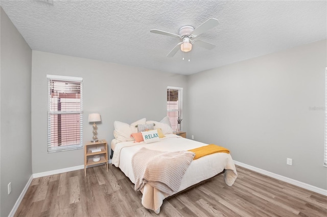 bedroom with ceiling fan, hardwood / wood-style floors, and a textured ceiling