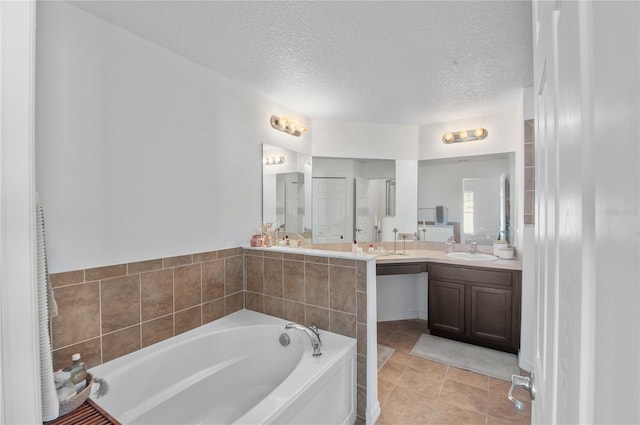 bathroom featuring vanity, a washtub, tile patterned floors, and a textured ceiling