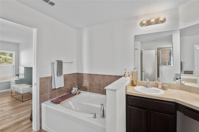 bathroom featuring a bathing tub, hardwood / wood-style floors, vanity, and a textured ceiling