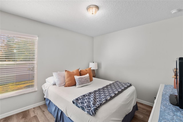 bedroom with hardwood / wood-style floors and a textured ceiling