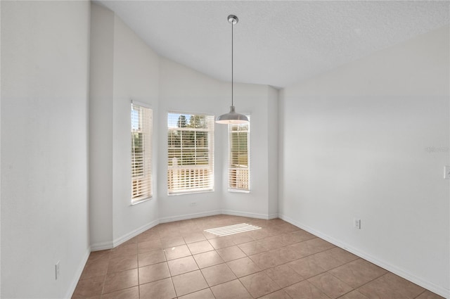 unfurnished dining area with lofted ceiling and light tile patterned floors