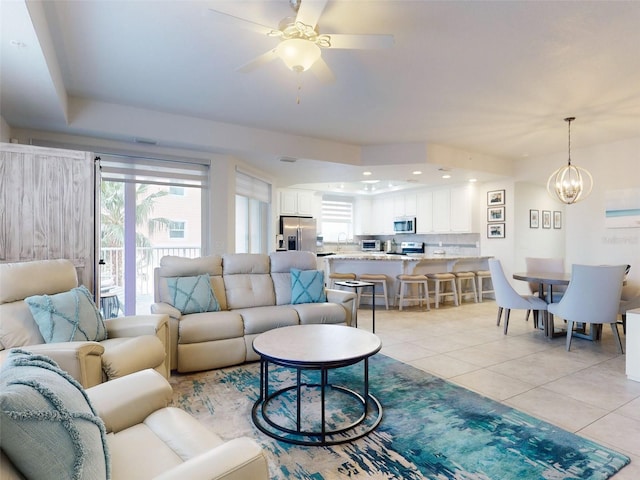 living room with a healthy amount of sunlight, ceiling fan with notable chandelier, and light tile patterned floors