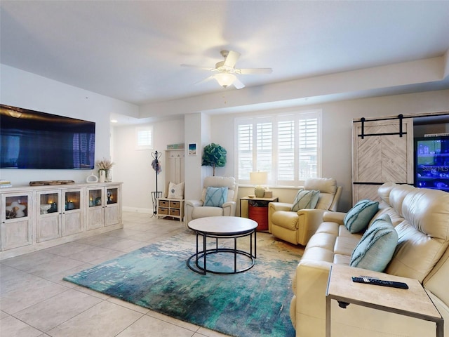 living room featuring light tile patterned floors, a barn door, and ceiling fan