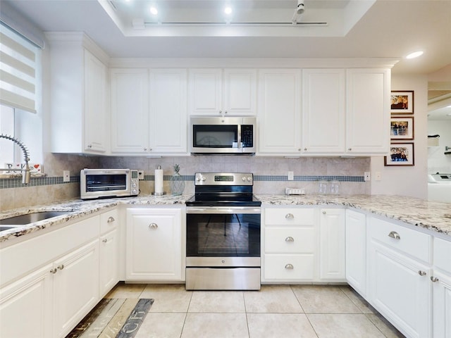 kitchen featuring white cabinetry, sink, backsplash, light tile patterned floors, and stainless steel appliances