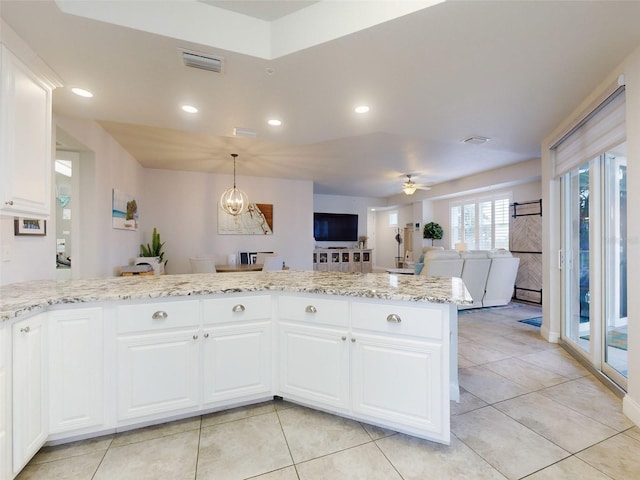 kitchen featuring light tile patterned floors, ceiling fan with notable chandelier, light stone countertops, and white cabinets