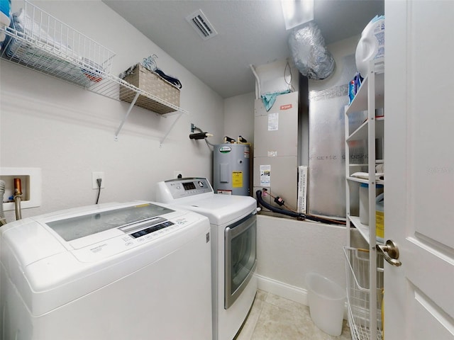 laundry room featuring heating unit, washer and clothes dryer, water heater, and light tile patterned flooring