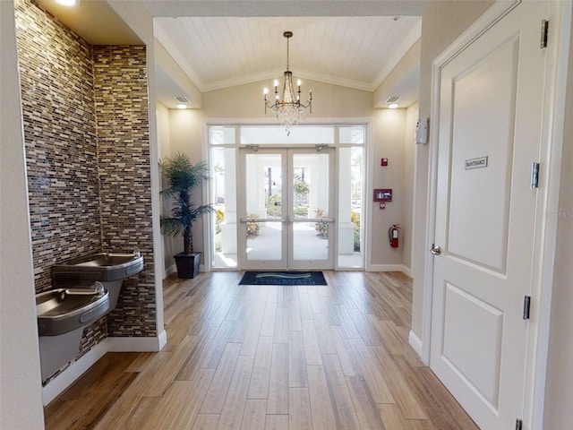 foyer with french doors, an inviting chandelier, light hardwood / wood-style floors, and vaulted ceiling