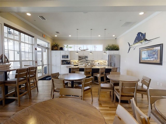 dining space featuring crown molding, french doors, and light wood-type flooring