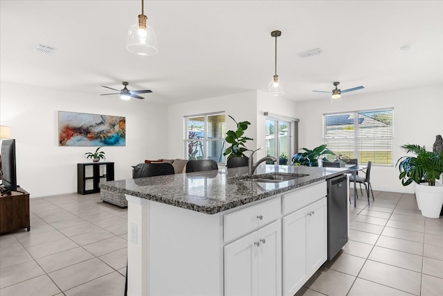 kitchen featuring sink, dark stone countertops, white cabinets, a center island with sink, and stainless steel dishwasher