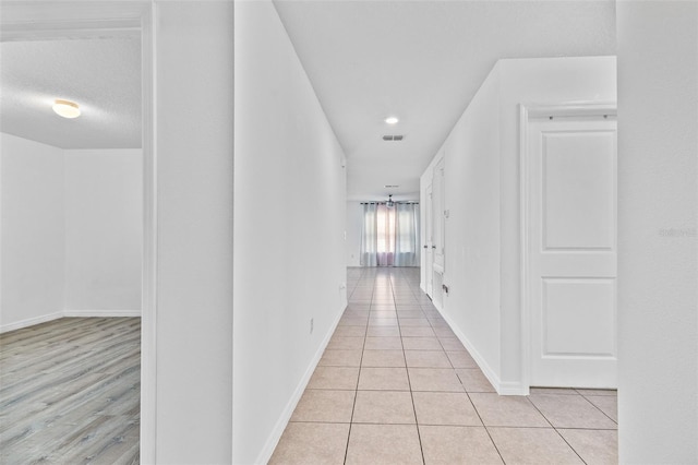 hallway featuring a textured ceiling and light tile patterned floors