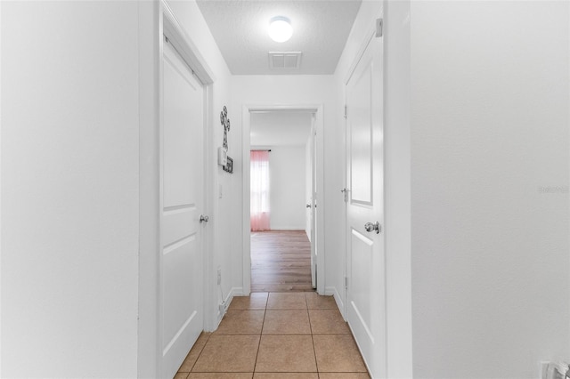 corridor featuring light tile patterned floors and a textured ceiling