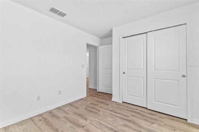 unfurnished bedroom with light wood-type flooring and a closet