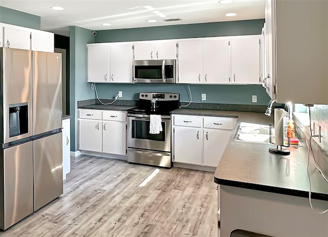 kitchen with stainless steel appliances, sink, light hardwood / wood-style flooring, and white cabinets