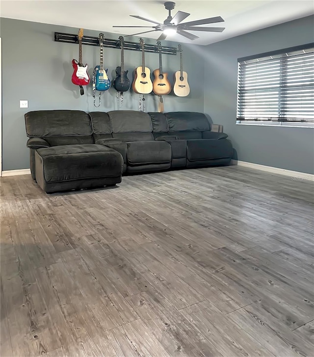 living area with a ceiling fan, baseboards, and wood finished floors