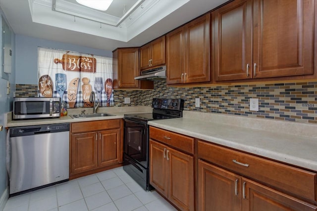 kitchen with sink, appliances with stainless steel finishes, tasteful backsplash, a tray ceiling, and light tile patterned flooring