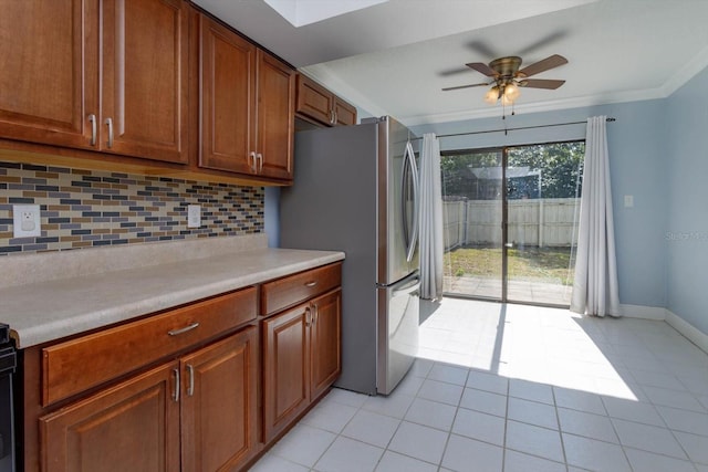 kitchen with light tile patterned floors, stainless steel refrigerator, ceiling fan, ornamental molding, and decorative backsplash