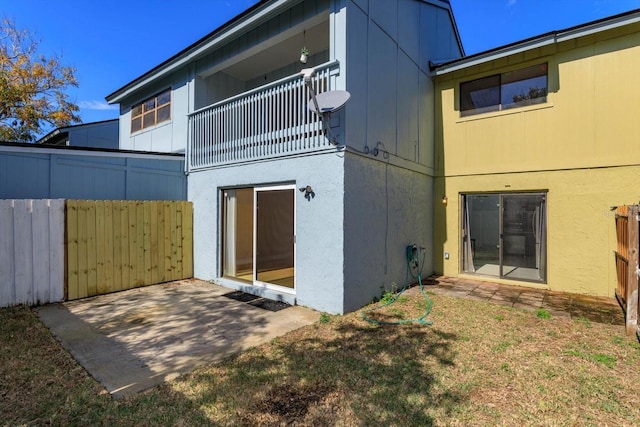 rear view of property featuring a patio, a balcony, and a yard