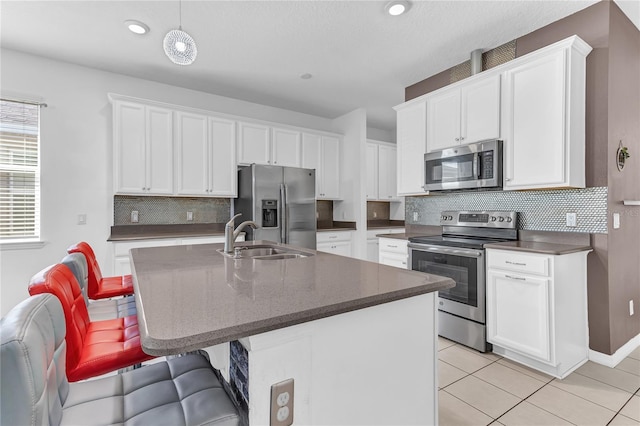 kitchen with white cabinetry, appliances with stainless steel finishes, sink, and an island with sink