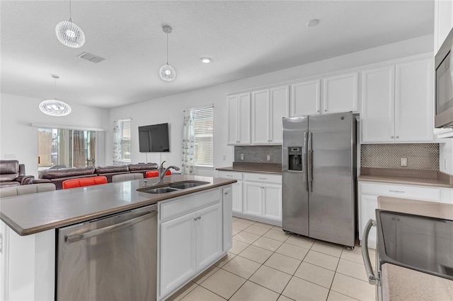 kitchen featuring stainless steel appliances, sink, hanging light fixtures, and white cabinets