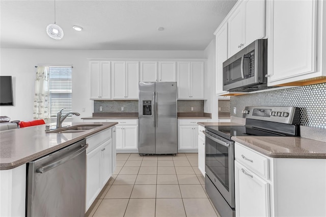 kitchen featuring light tile patterned flooring, appliances with stainless steel finishes, pendant lighting, white cabinetry, and sink