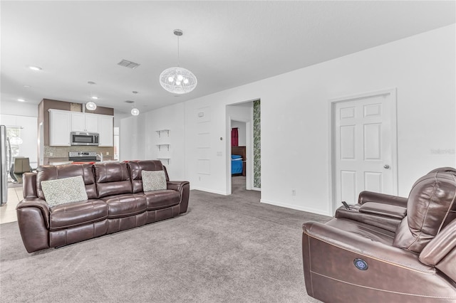 carpeted living room featuring a notable chandelier