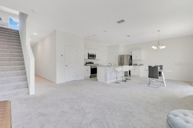 unfurnished living room featuring light carpet and a notable chandelier