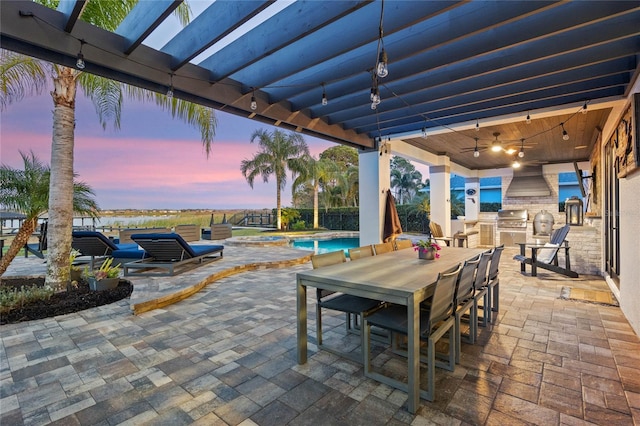 patio terrace at dusk with an outdoor kitchen and a grill