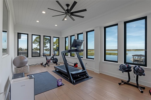 exercise area featuring wood ceiling, light hardwood / wood-style flooring, ornamental molding, and a water view