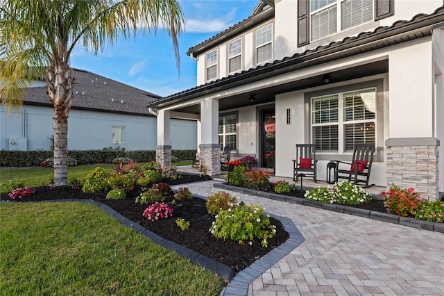 view of exterior entry with a yard and a porch