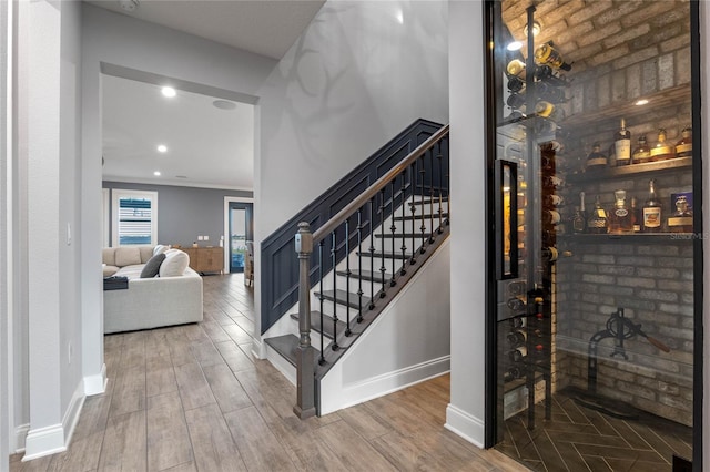 stairs with wood-type flooring and ornamental molding