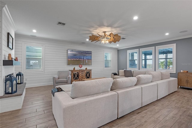 living room with plenty of natural light, ornamental molding, wooden walls, and light wood-type flooring