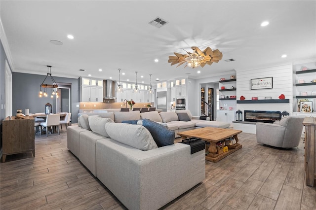 living room with ornamental molding and ceiling fan with notable chandelier