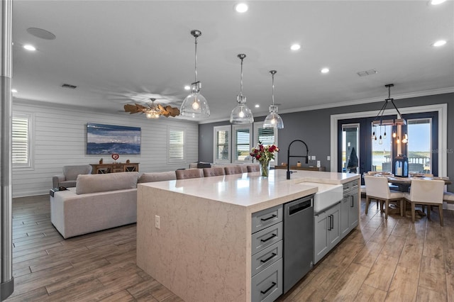 kitchen with sink, decorative light fixtures, a center island with sink, ornamental molding, and dishwasher