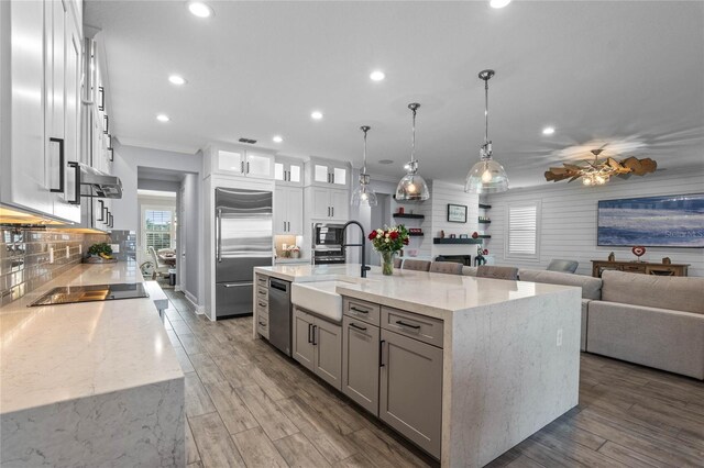 kitchen with a spacious island, appliances with stainless steel finishes, decorative light fixtures, and light hardwood / wood-style floors